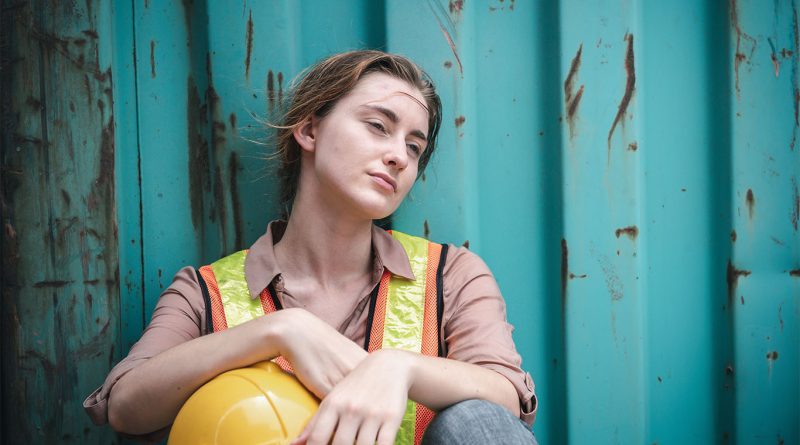 Image of young girl sat against a wall in a high-vis and hard hat to support H2S scrapping article