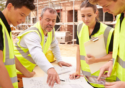 Construction workers gather round plans