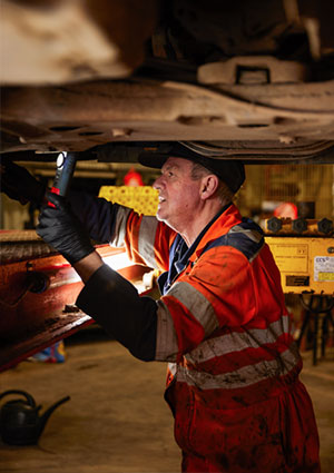 Mechanic inspecting underside of vehicle