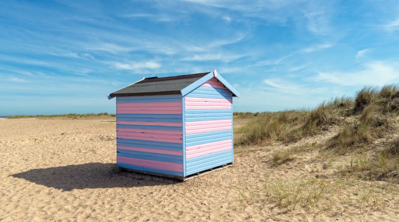 A wooden beach hut under construction on Great Yarmouth, with a scenic sea view in the background.