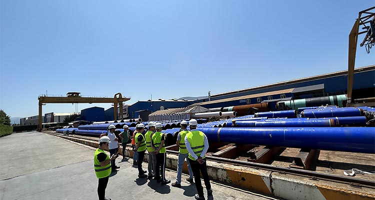 Men in hard hats & high visibility jackets standing in front of blue pipes