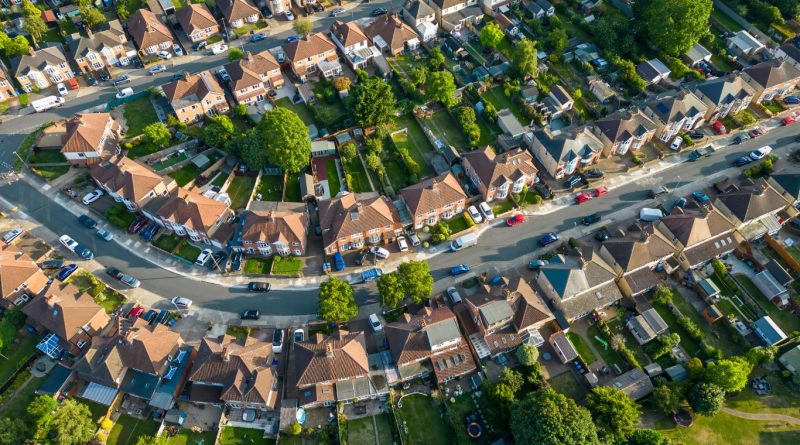 Aerial view of a suburban UK neighbourhood with rows of houses, gardens, and curved streets, reflecting modern urban development.