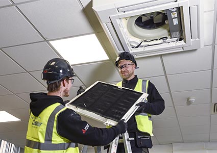 Workers installing ceiling air conditioning unit