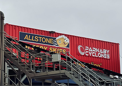 a large red shipping container advertising two businesses: Allstone Speedy Skips and Parnaby Cyclones