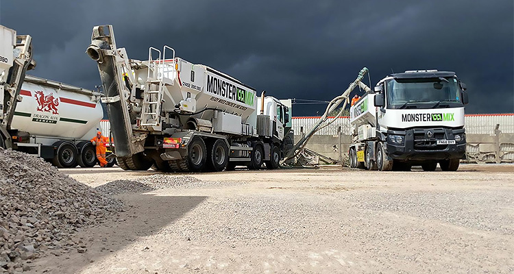 How Allstone is leveraging its experience to execute an ambitious growth strategy construction site featuring several concrete mixer trucks under a dark, cloudy sky. In the foreground, there's a pile of aggregate material.