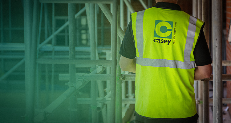 a worker wearing a high-visibility vest with the logo and name "Casey PRO-ENVIRONMENT".
