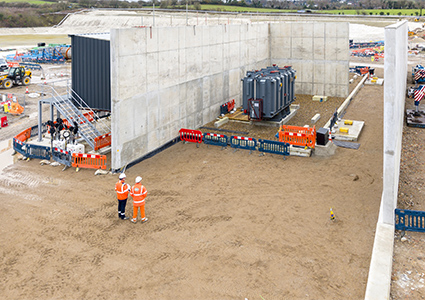 a construction site featuring a large electrical transformer within a concrete enclosure