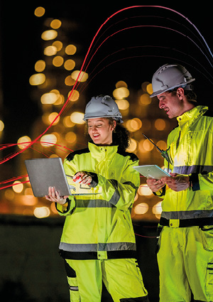 two individuals wearing high-visibility yellow industrial work jackets with reflective safety stripes.