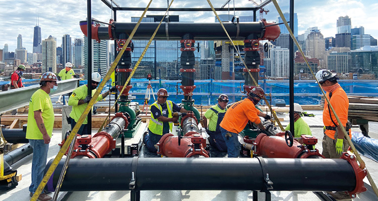 construction workers installing large-diameter black pipes and industrial valves