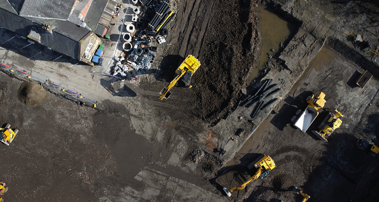 construction machinery, including excavators and a tipper truck, operating at a site in Swansea during sinkhole repairs