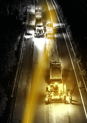 an aerial view of a highway resurfacing crew operating at night.