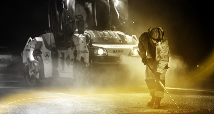 road construction workers performing asphalt paving or repairs at night