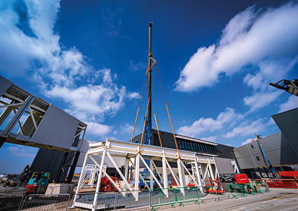 a white steel modular structure being lifted by a crane