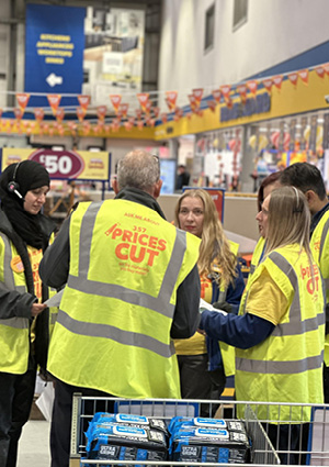 people in neon yellow vests branded with "Prices Cut" promoting a sale
