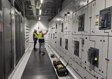 two technicians working inside an electrical plant switchgear room or data center power control facility