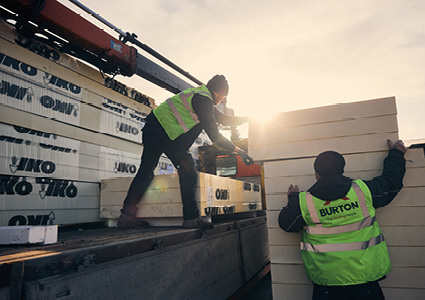 Workers are unloading pallets of IKO building materials