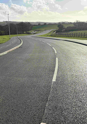a newly installed asphalt surface, concrete curbing, and white painted edge lines