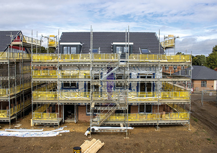 a multi-story residential building undergoing construction with extensive scaffolding and safety netting installed around the exterior