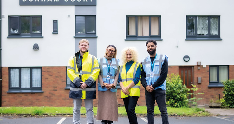 a team standing in front of a residential building named Durham Court