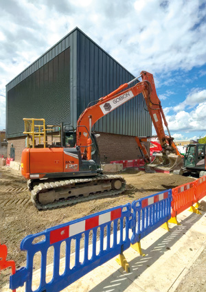 an orange medium tracked excavator operating on an outdoor construction or civil engineering site