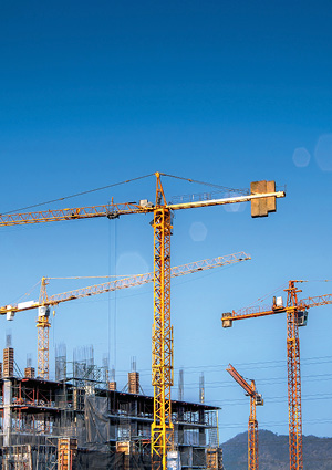 Yellow construction cranes on a concrete building site under a clear blue sky