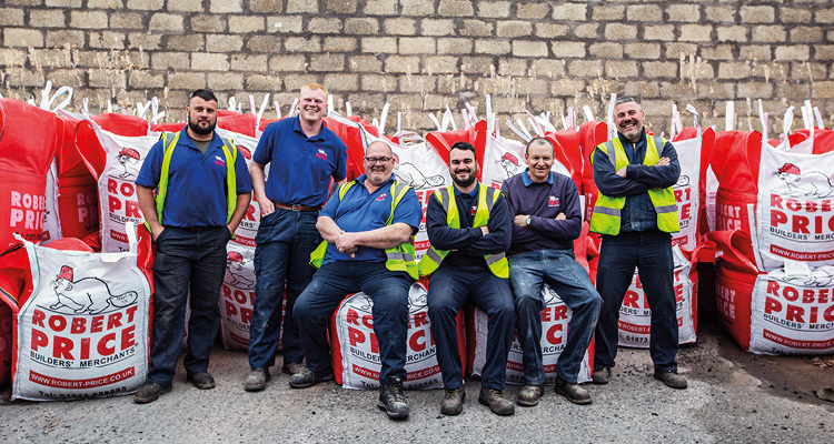 employees of Robert Price Builders' Merchants posing in branded blue work uniforms and high-visibility vests