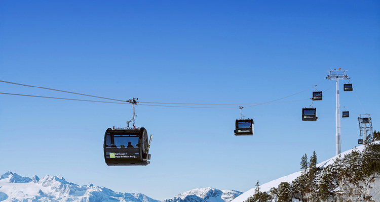 a scenic view of a cable car system operating in a snowy mountain region under a clear, bright blue sky