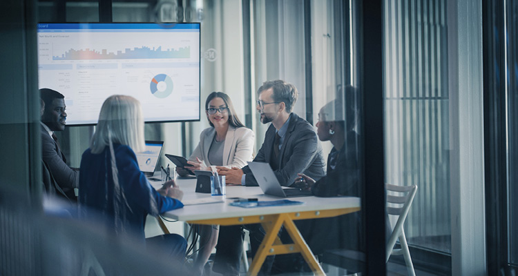 a diverse corporate team holding a strategy meeting in a modern glass-walled office, reviewing financial dashboards and charts on a screen